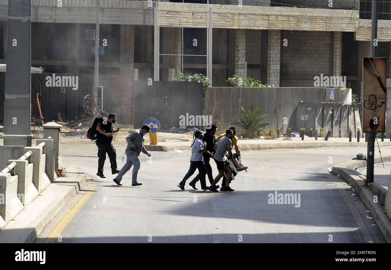 Beirut, Lebanon. 14th Oct, 2021. Civilians run for cover amidst clashes in the area of Tayouneh, in the southern suburb of the capital Beirut, onThursday on October 14, 2021. Armed clashes broke out in Beirut Thursday during the protest against the lead judge investigating last year's massive blast in the city's port, as tensions over the domestic probe boiled over. photo by Jamal Eddine/ Credit: UPI/Alamy Live News Stock Photo
