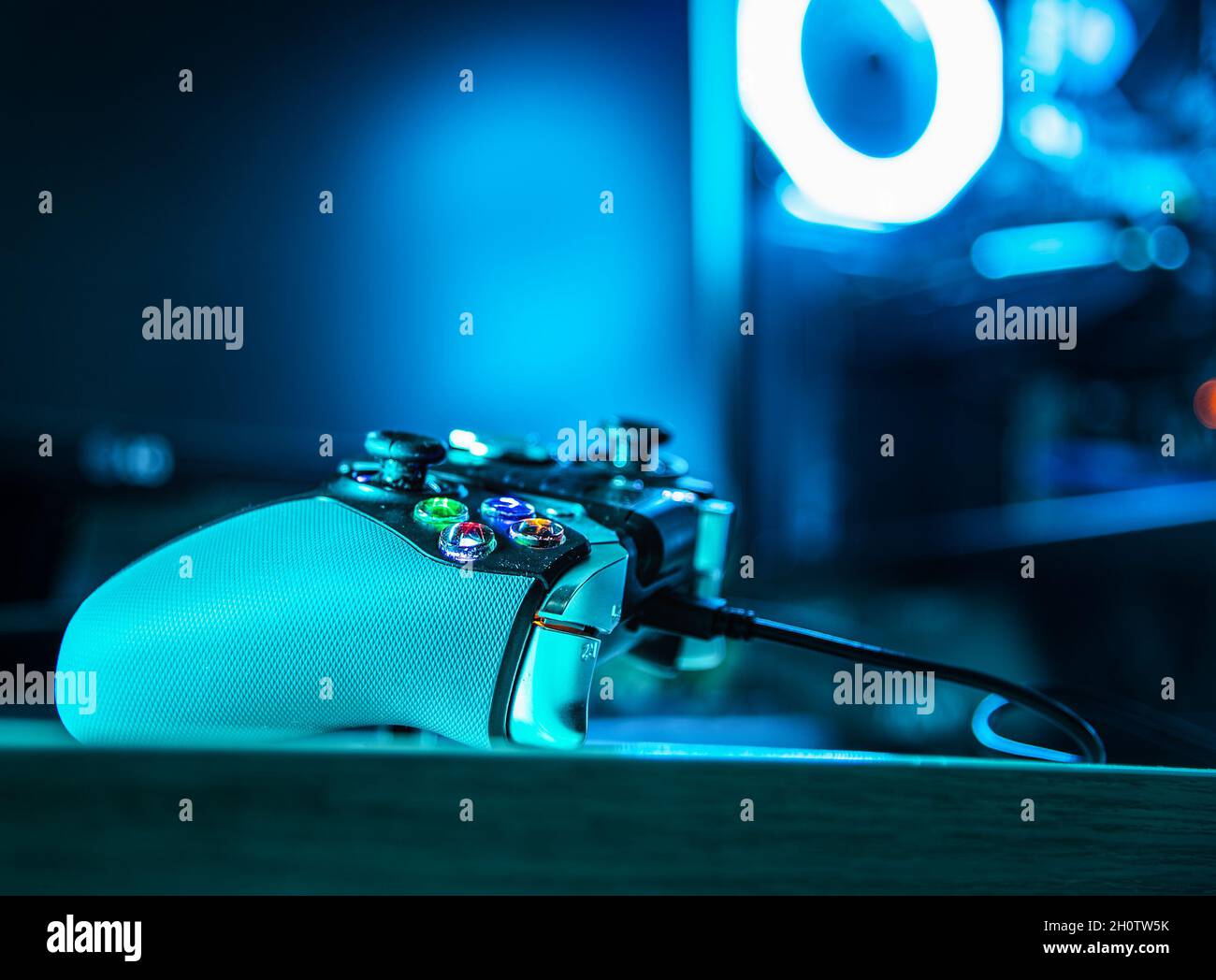 Game controller with a pc rgb case on the background in a dark room ...