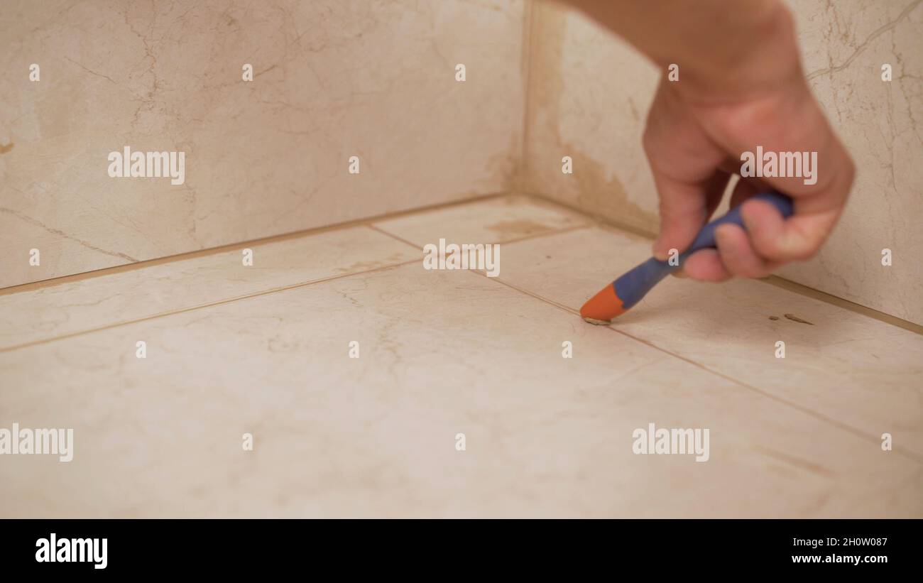 Cleaning tile joints on the floor. Laying floor tiles, tiler cleaning