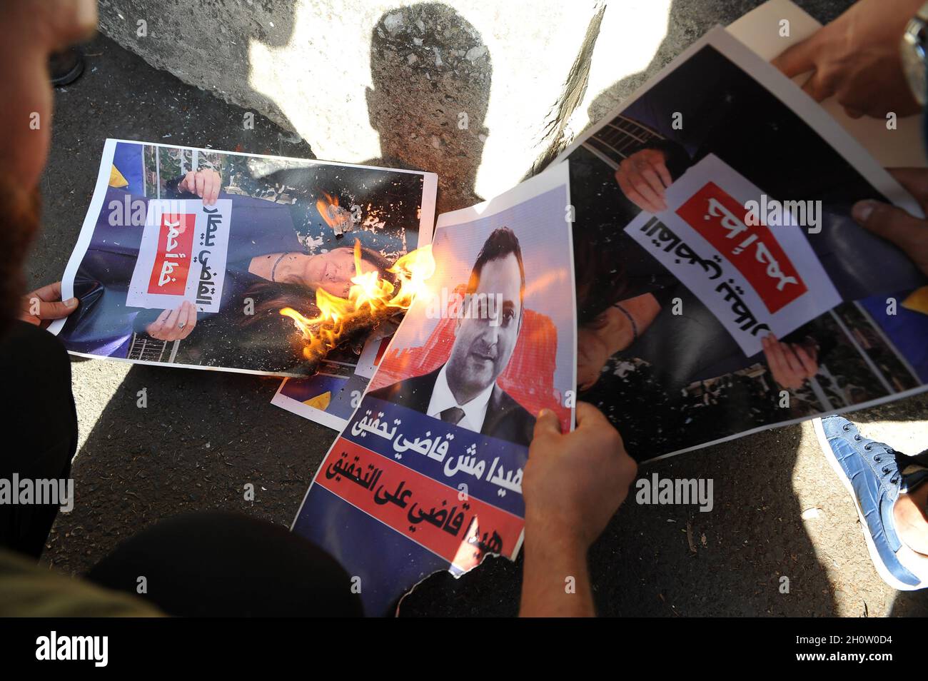 Beirut, Lebanon. 14th Oct, 2021. A poster with a picture of Judge Tarek Bitar who is investigating last year's deadly seaport blast, is set on fire by supporters of the Shiite Hezbollah and Amal groups, during a protest in front of the Justice Palace, in Beirut, Lebanon, on Thursday on October 14, 2021. Armed clashes broke out in Beirut Thursday during the protest against the lead judge investigating last year's massive blast in the city's port, as tensions over the domestic probe boiled over. photo by Jamal Eddine/ Credit: UPI/Alamy Live News Stock Photo