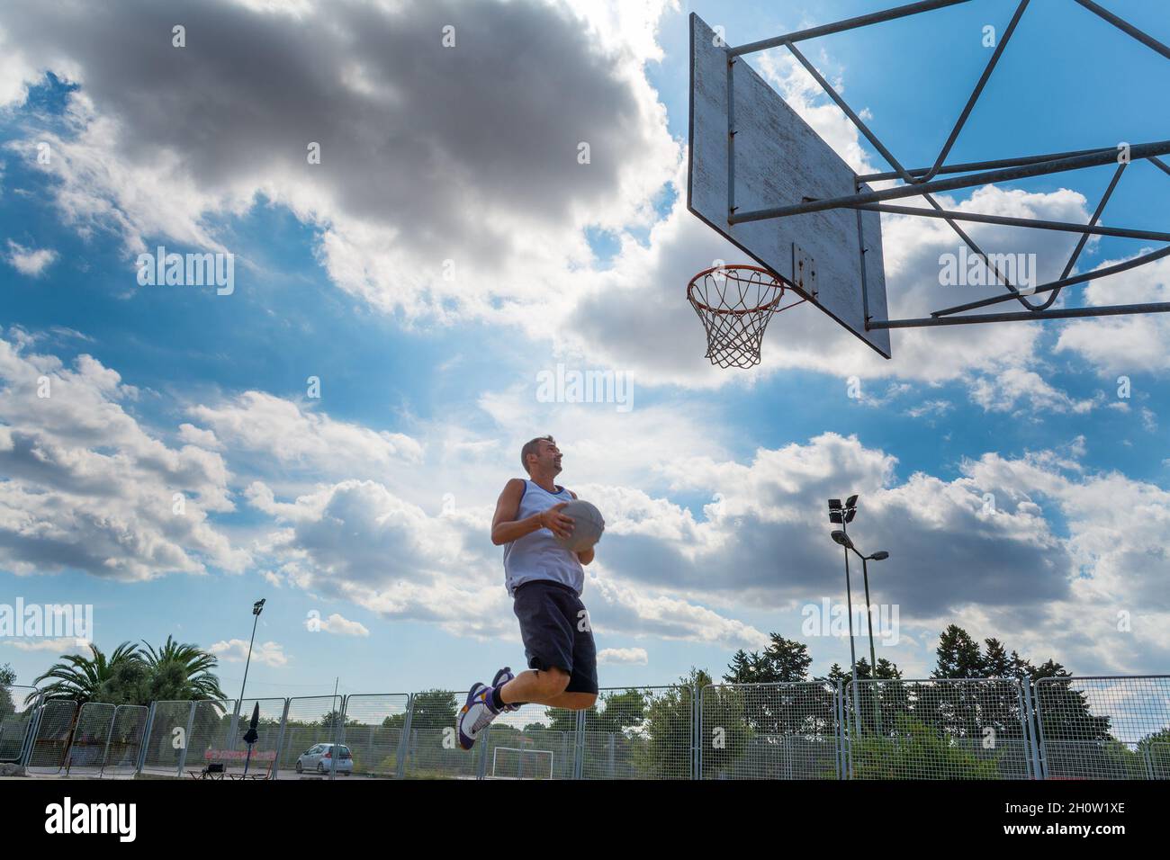 Basketball player jumping to the hoop under a cloudy sky Stock Photo Alamy