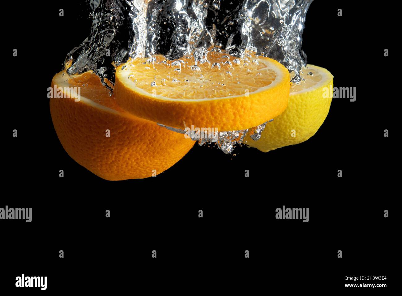 Fresh sliced orange and lemon in water splash isolated on black ...