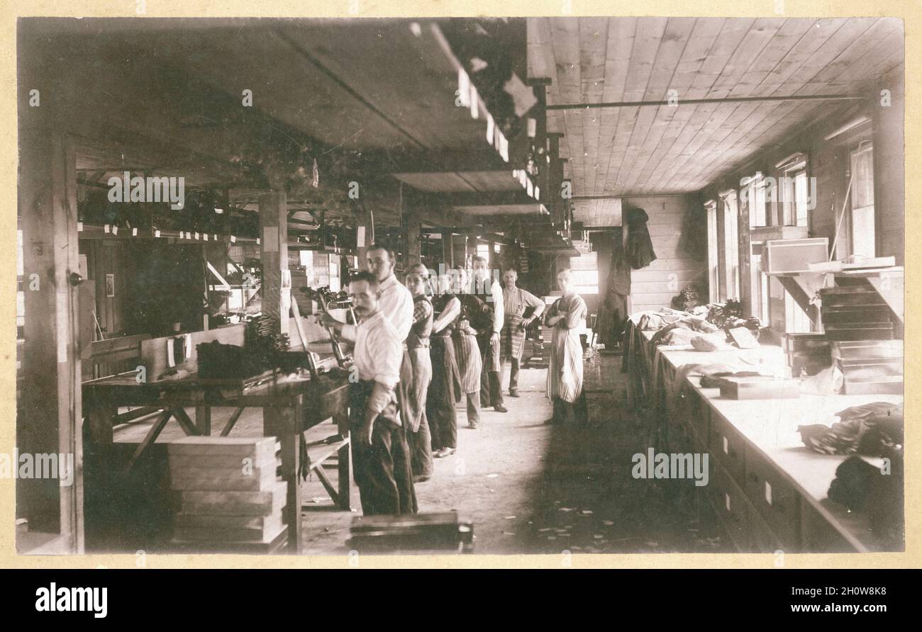 Workers making gloves in a workshop, Gloversville, New York, circa 1900. Stock Photo