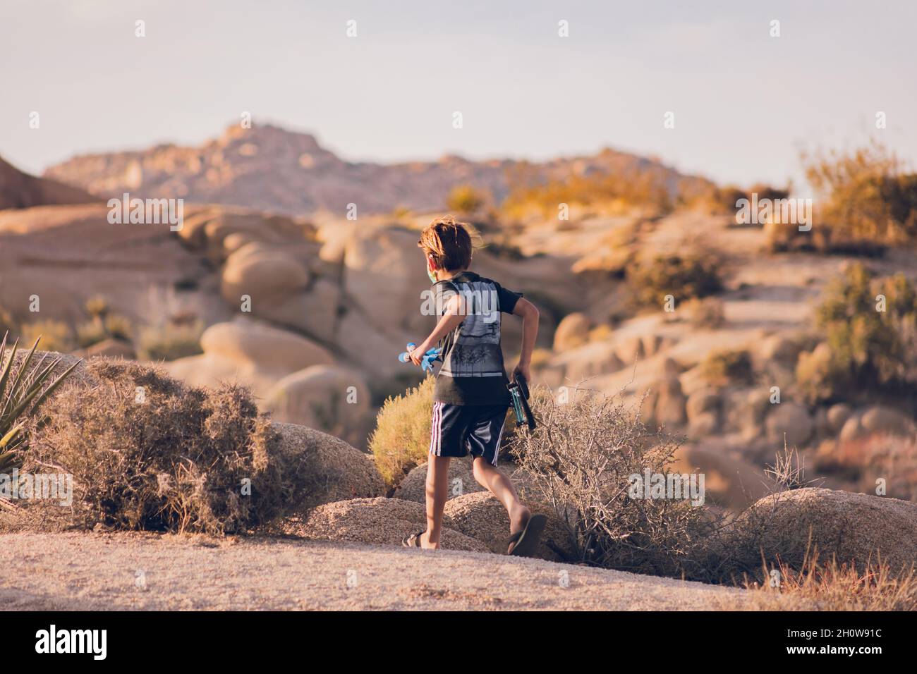 Boy running in the desert with a bow and arrow. Stock Photo