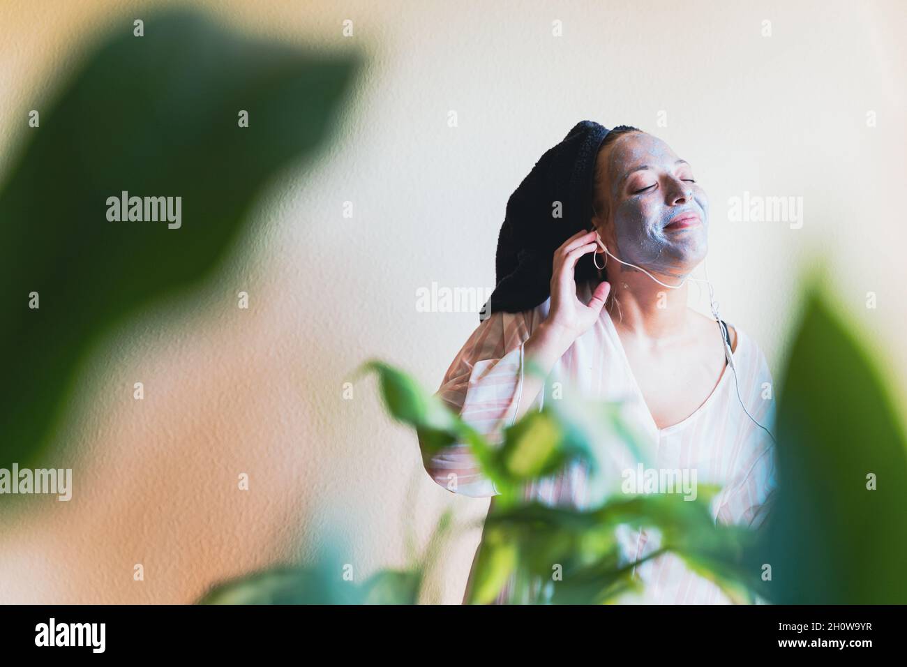 Young woman listening music while having skin care spa day at home