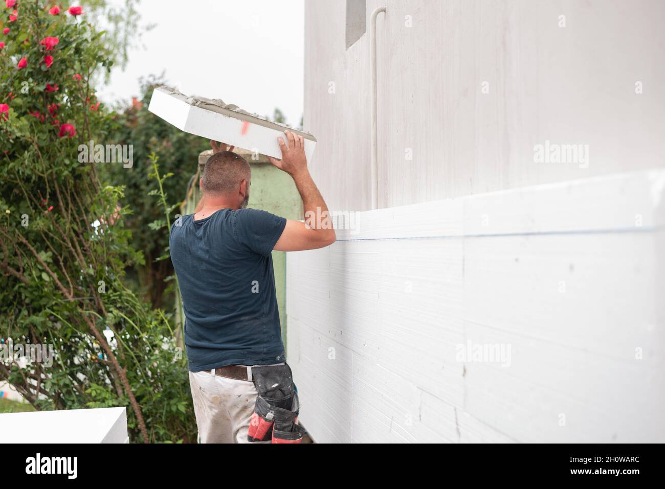 Insulation of the house with polyfoam. The worker is installing a styrofoam  board on the facade Stock Photo - Alamy