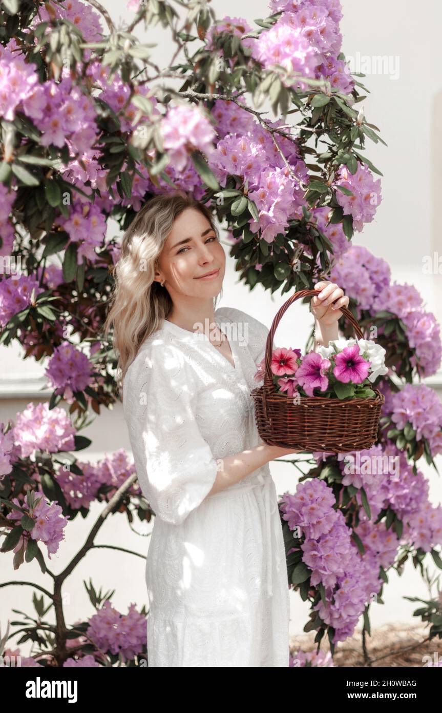 Romantic girl with a basket in the rhododendron bushes. Stock Photo