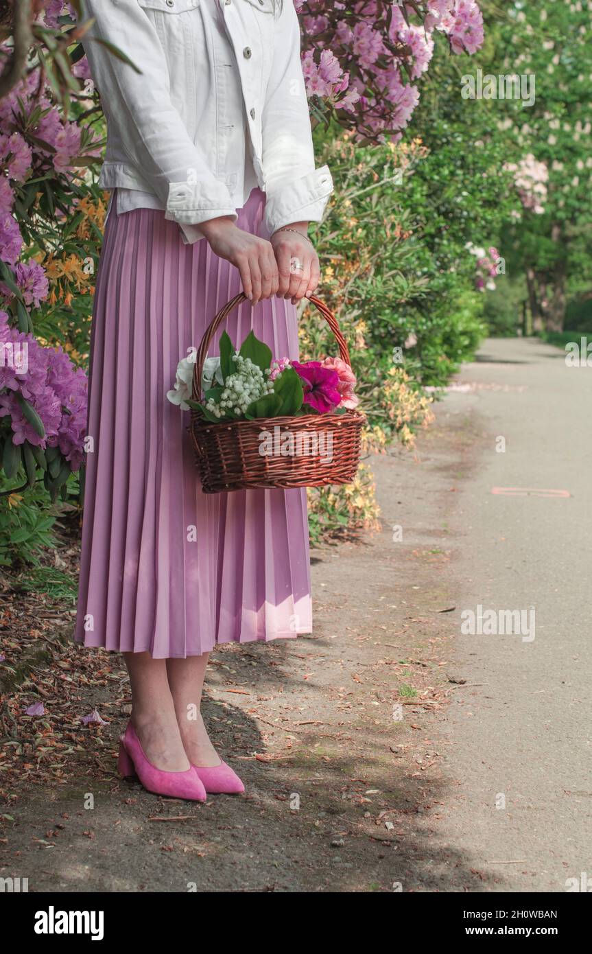 A basket with lilies of the valley and petunias in the hands. Stock Photo