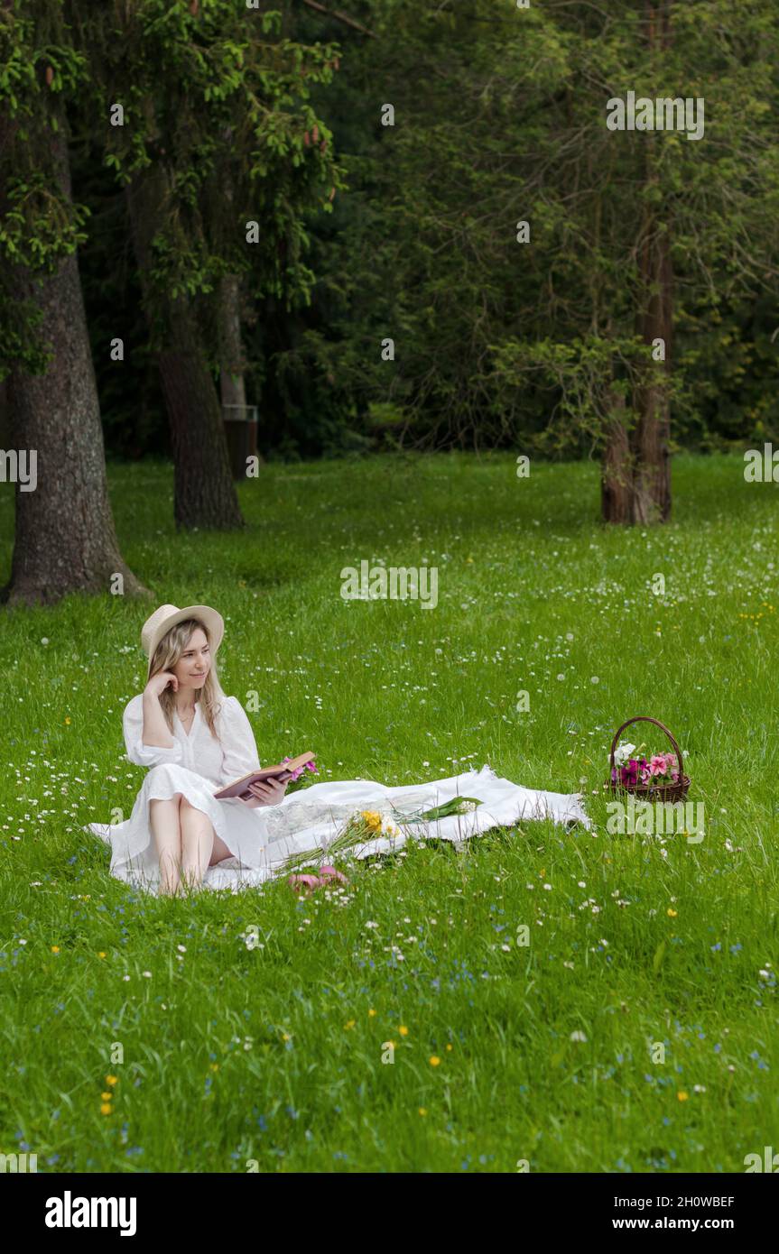 Girl with a book on a blanket in the forest. Stock Photo