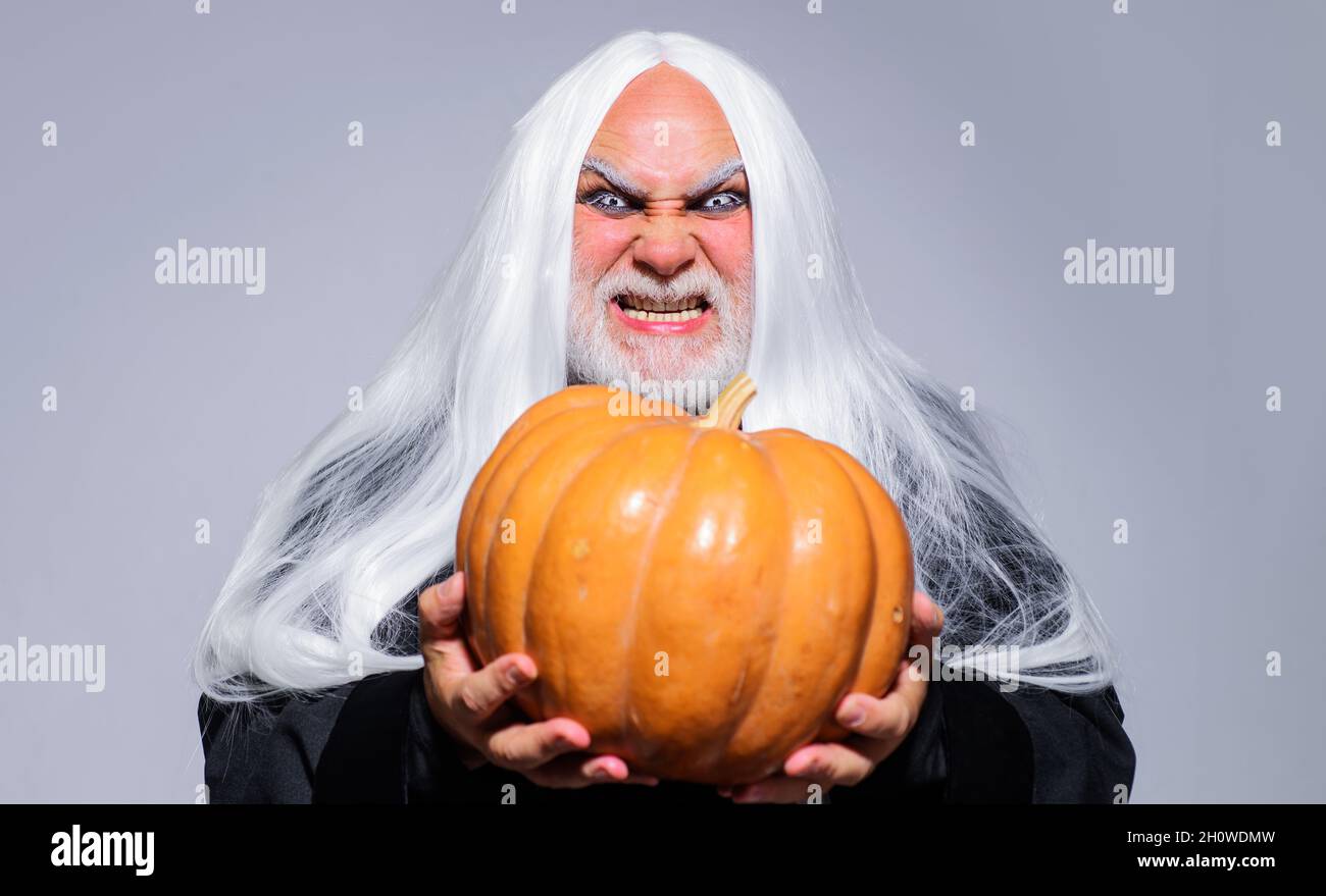 Fantasy horror Halloween. Wicked Devil man with Jack-o-lantern. Angry Demon on Halloween night. Evil wizard with orange pumpkin. Stock Photo