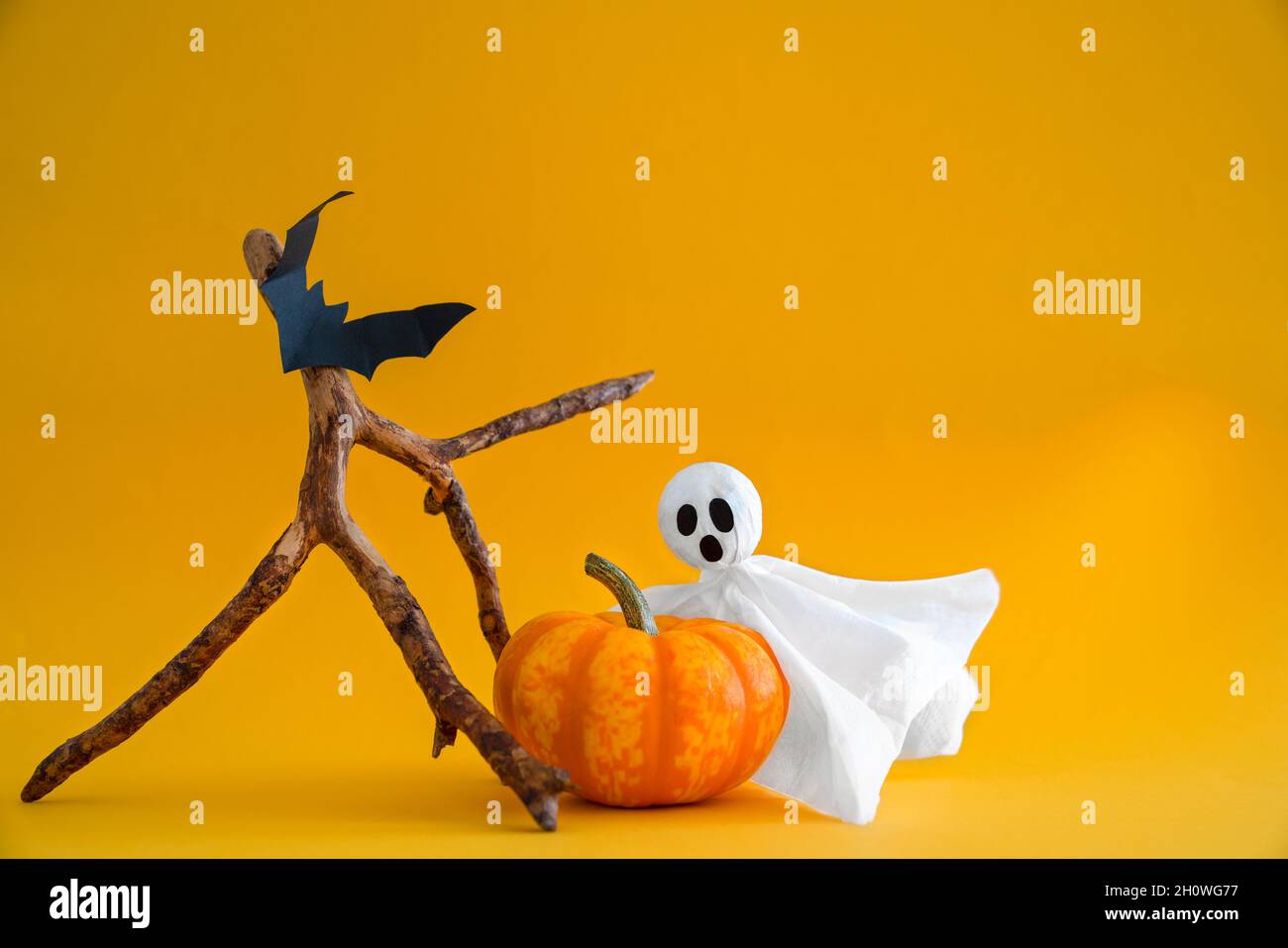 Ghost, pumpkin and bats on orange background with copy space. Concept of Halloween Stock Photo