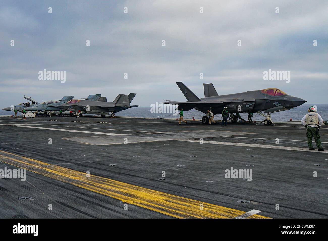 Naval flight operations take place aboard a aircraft carrier featuring F/A-18 Super Hornets and F-35C Joint Strike Fighter Stock Photo