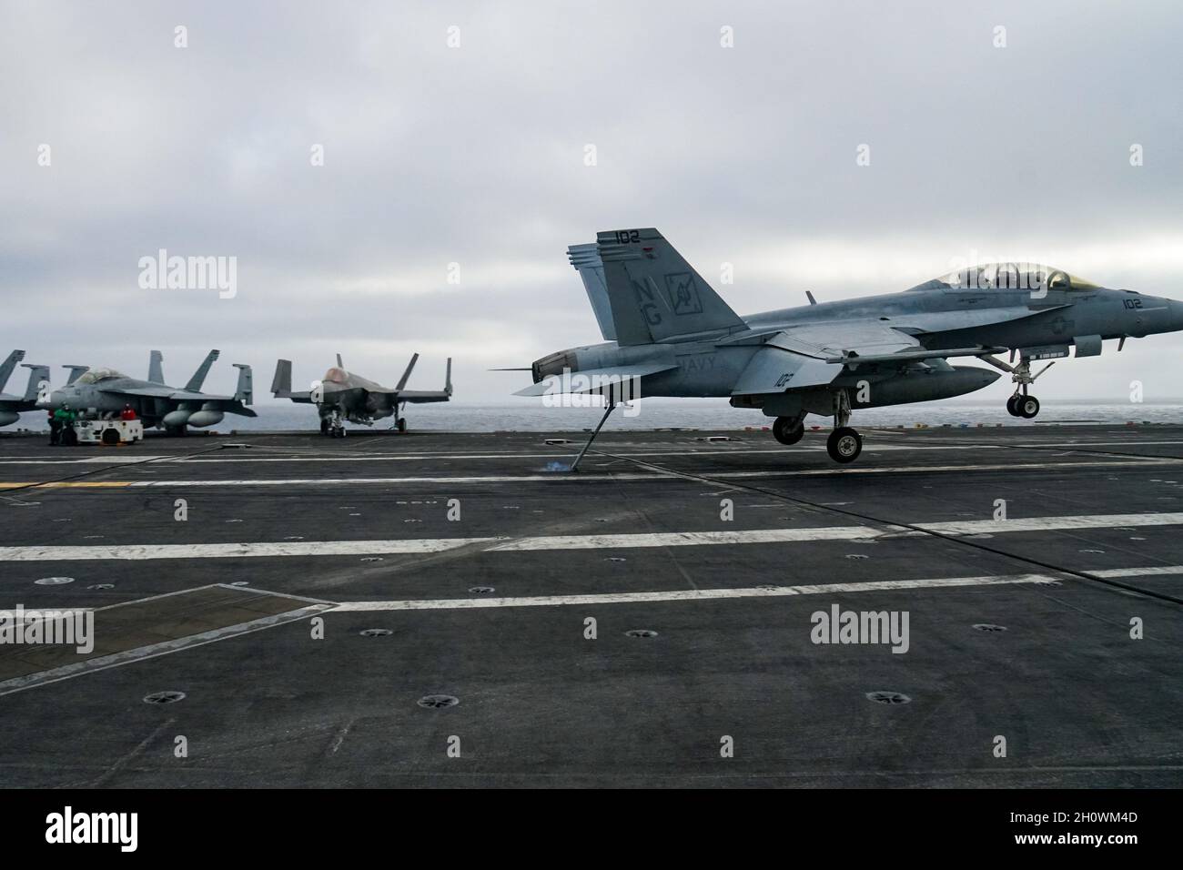 Naval flight operations take place aboard a aircraft carrier featuring F/A-18 Super Hornets and F-35C Joint Strike Fighter Stock Photo