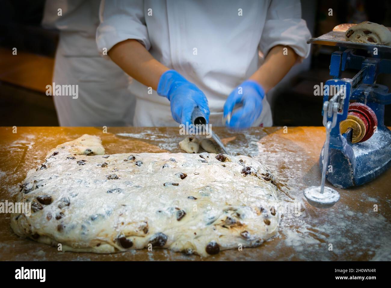 A baker cuts and weighs dough on a scale for chocolate chip cookies at a bakery in Hiroshima, Japan. Stock Photo
