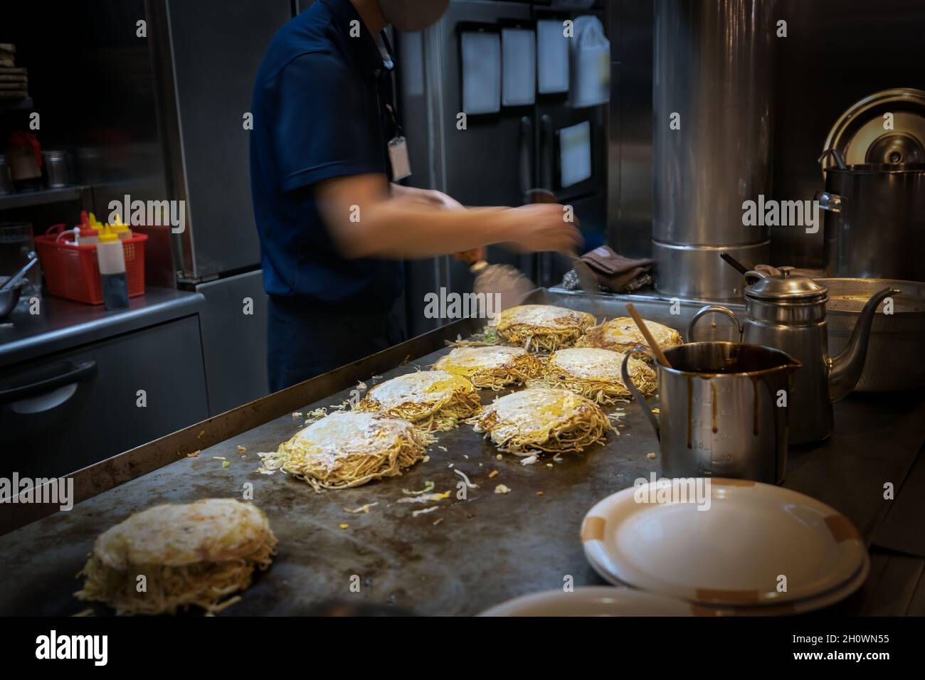 A chef prepares a favorite local dish called okonomiyaki at kitchen in Hiroshima, Japan Stock Photo