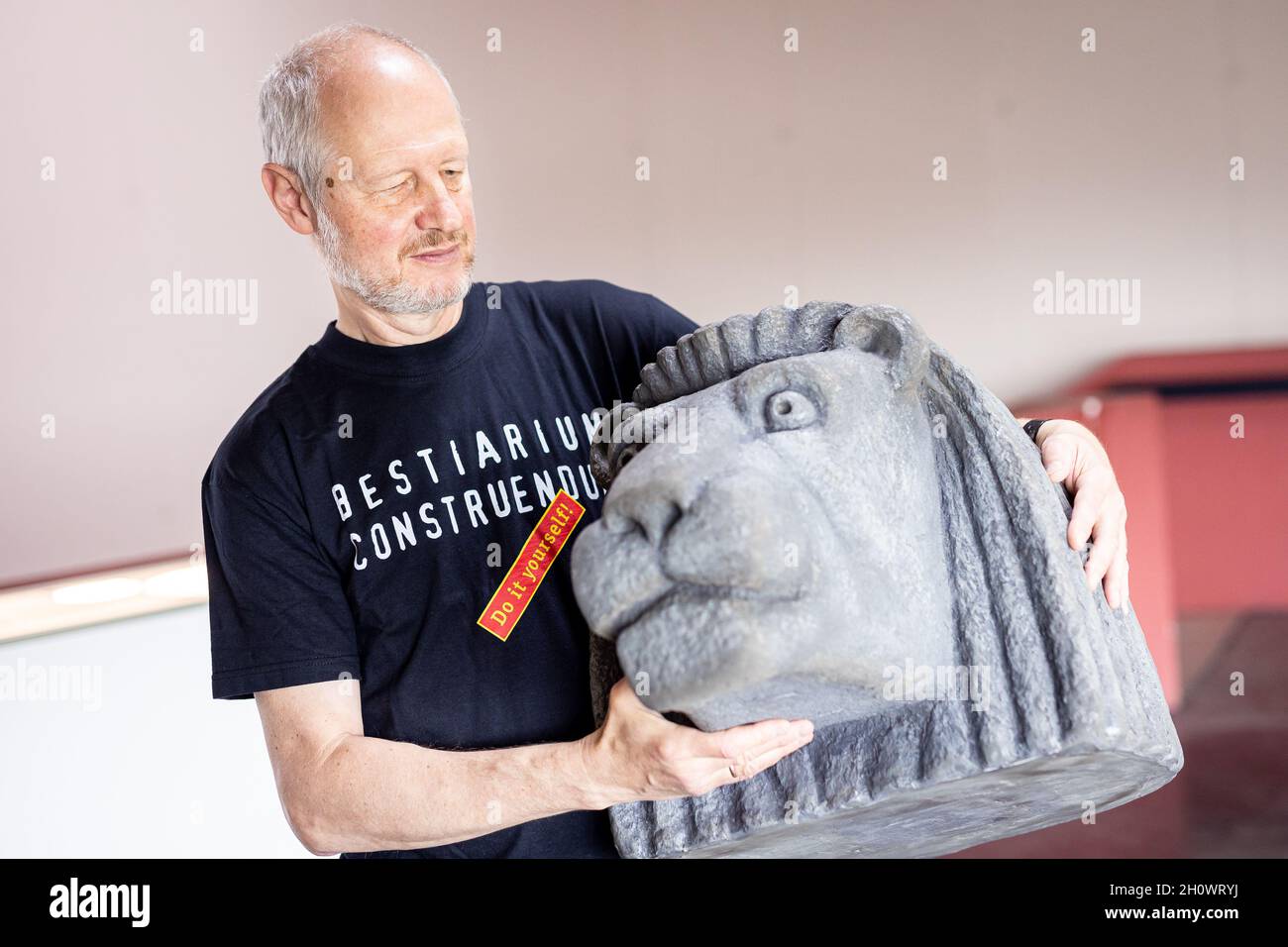 14 October 2021, Lower Saxony, Schöningen: Artist Alexander Reichstein stands in the Schöningen Research Museum with a model of a lion's head. From 16.10.2021 to 27.02.2022 the museum presents the interactive exhibition 'Bestiarium Construendum'. Visitors can create their own mythical creatures. Photo: Moritz Frankenberg/dpa Stock Photo