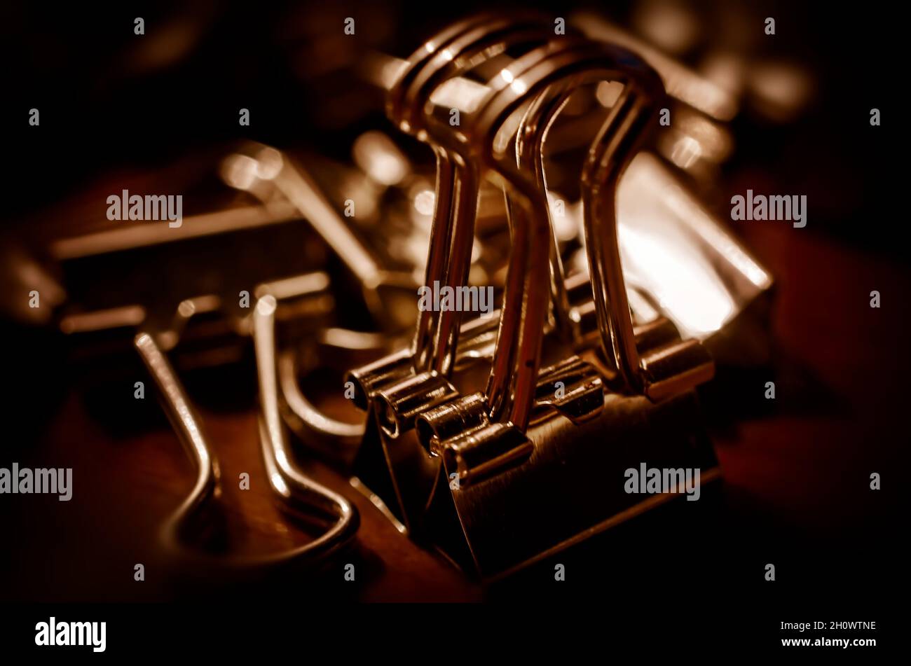 Metal binder clips, also known as foldback clips and bulldog clips, are scattered on a desk, July 20, 2016, in Coden, Alabama. Stock Photo