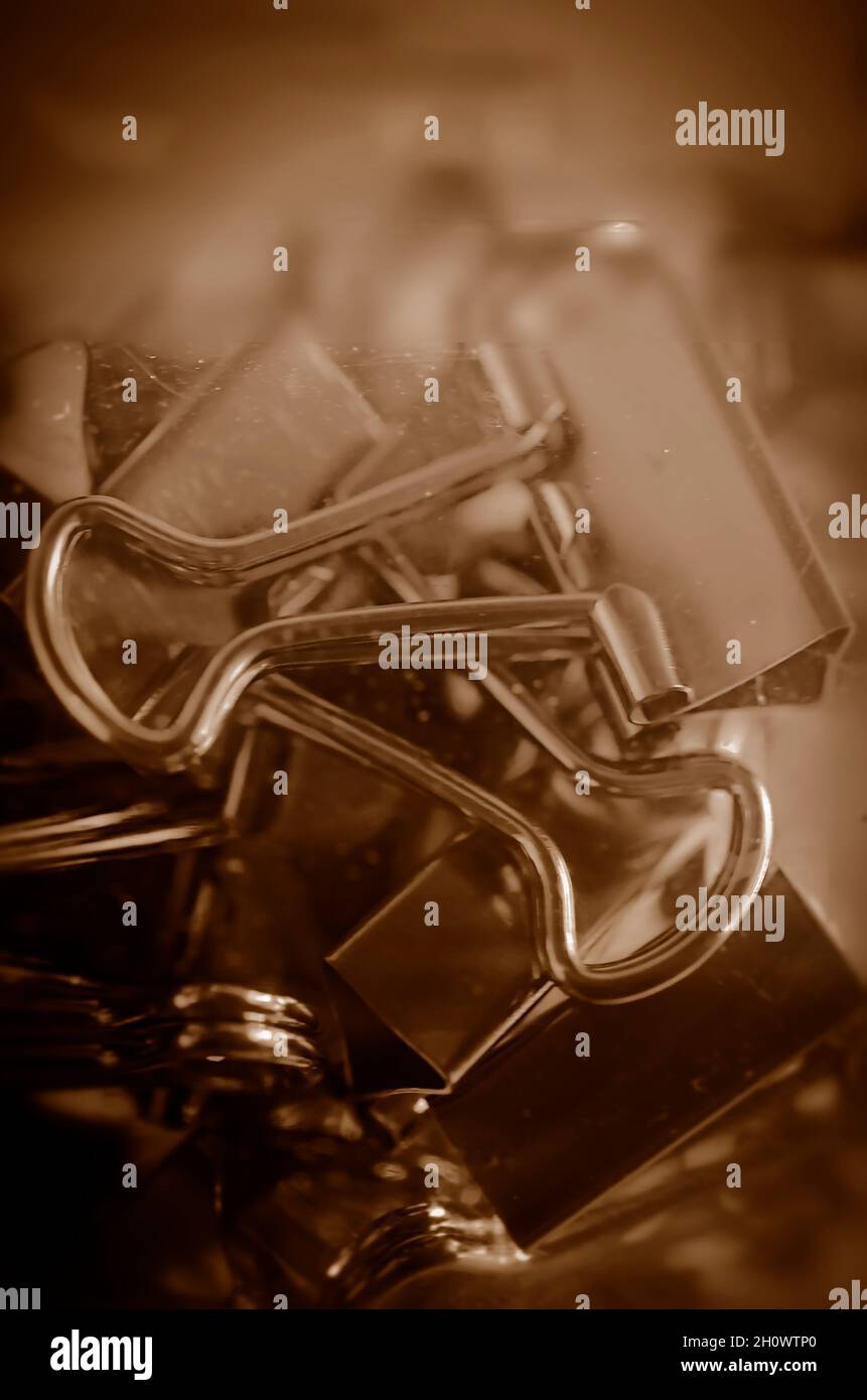 Metal binder clips, also known as foldback clips and bulldog clips, are scattered on a desk, July 20, 2016, in Coden, Alabama. Stock Photo