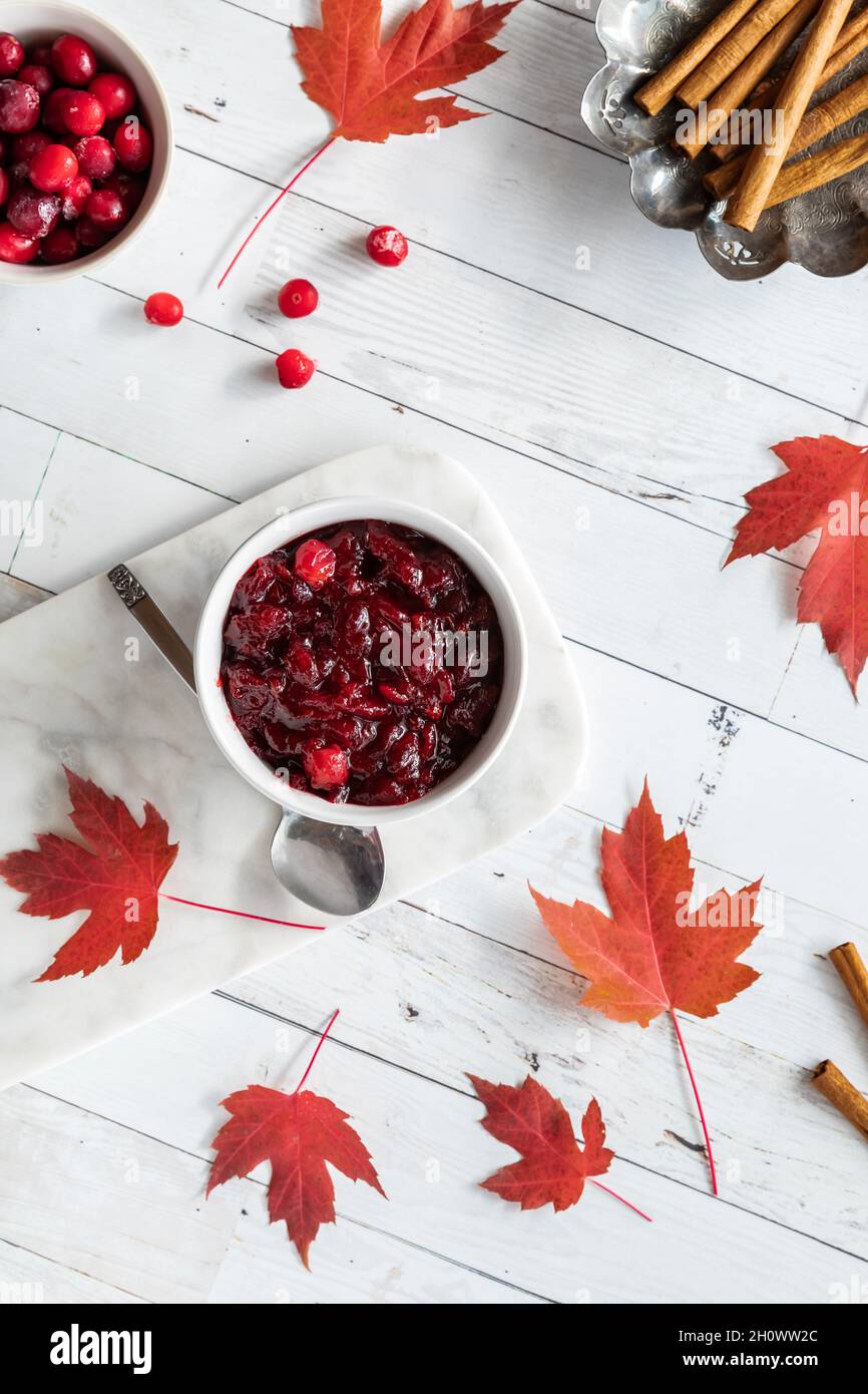 Top down view of a bowl of homemade cranberry sauce surrounded by maple leaves. Stock Photo