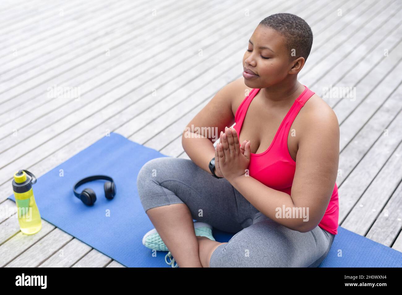 African american plus size woman in sports clothes sitting on mat