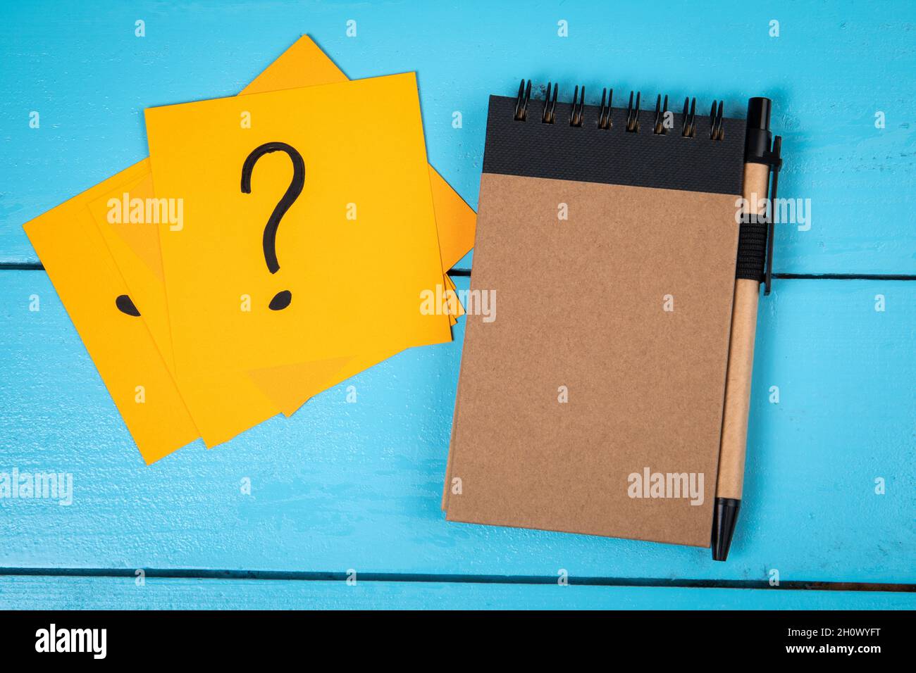 Notepad and note papers with question marks. Blue board table Stock