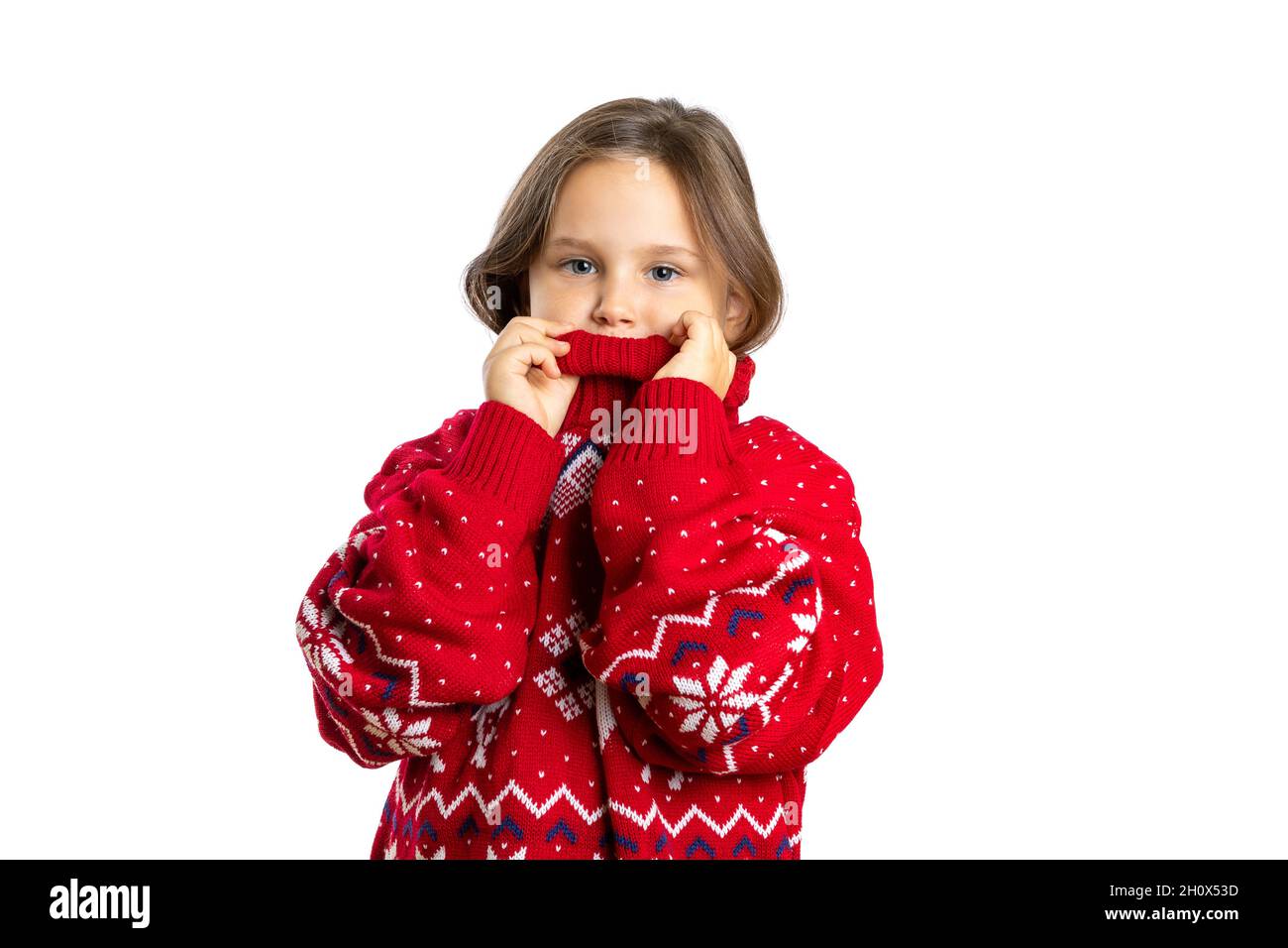 portrait of beautiful girl in oversize red knitted Christmas sweater with reindeer touching high collar, isolated on white background Stock Photo