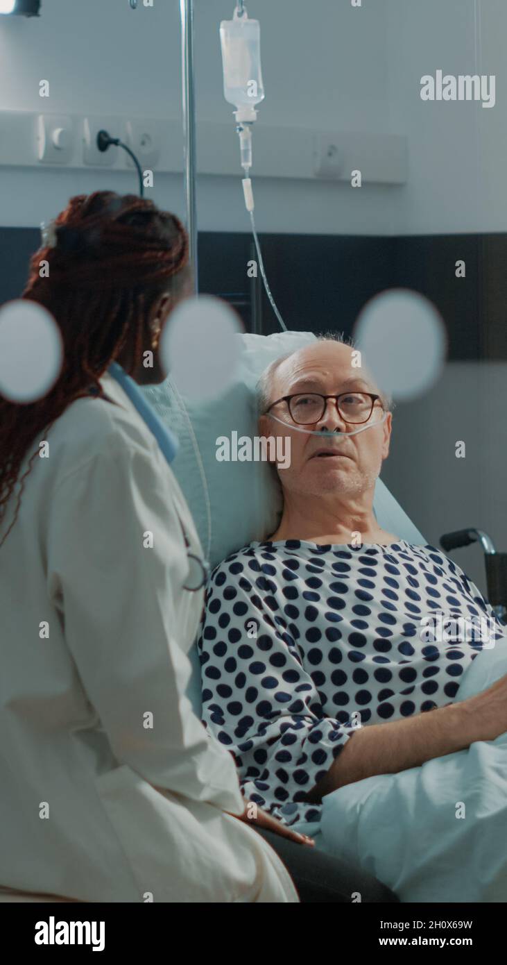 Nurse and african american doctor tending to ill patient in hospital ...