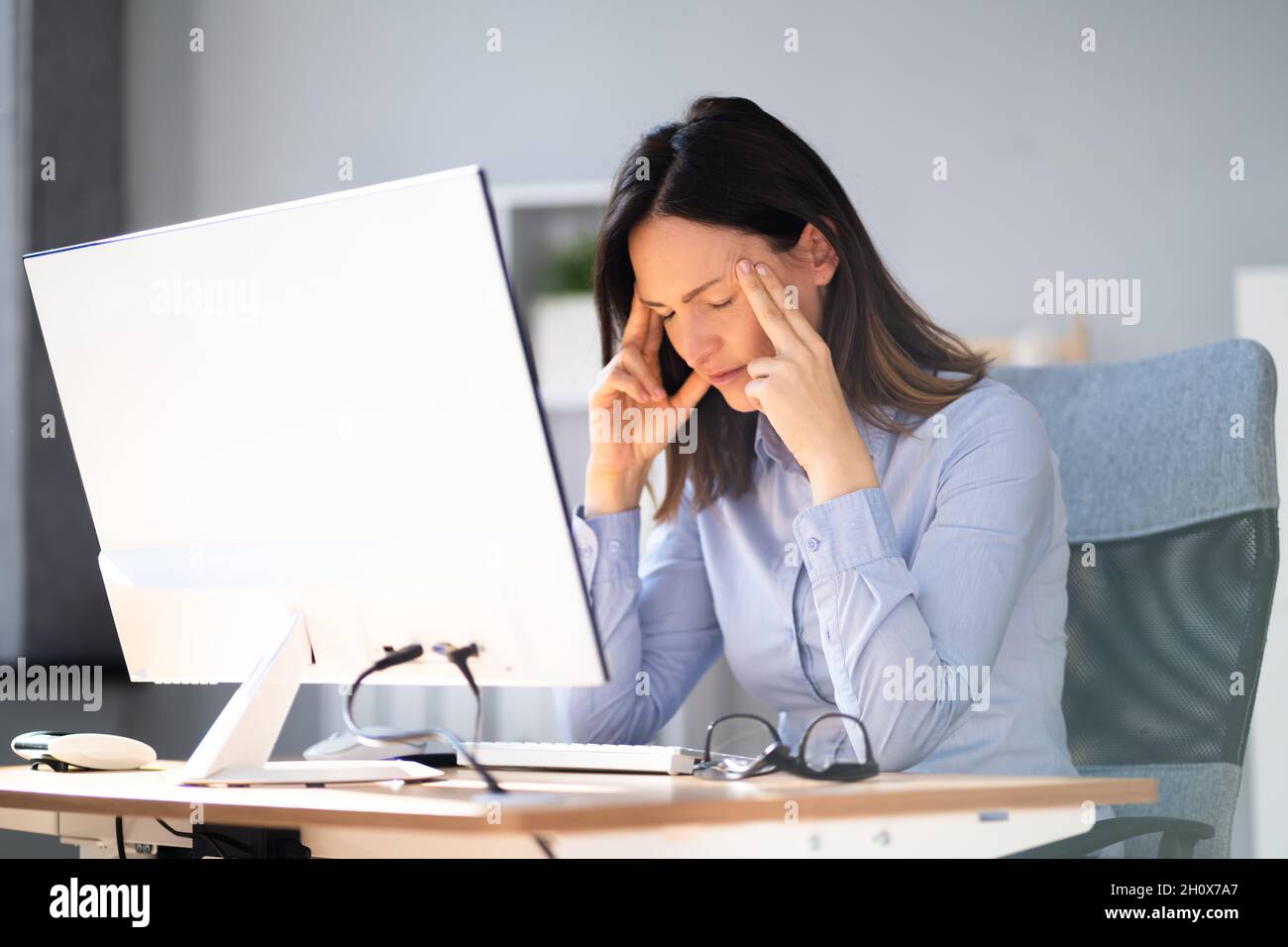 Depressed Business Woman In Office With Headache Stock Photo