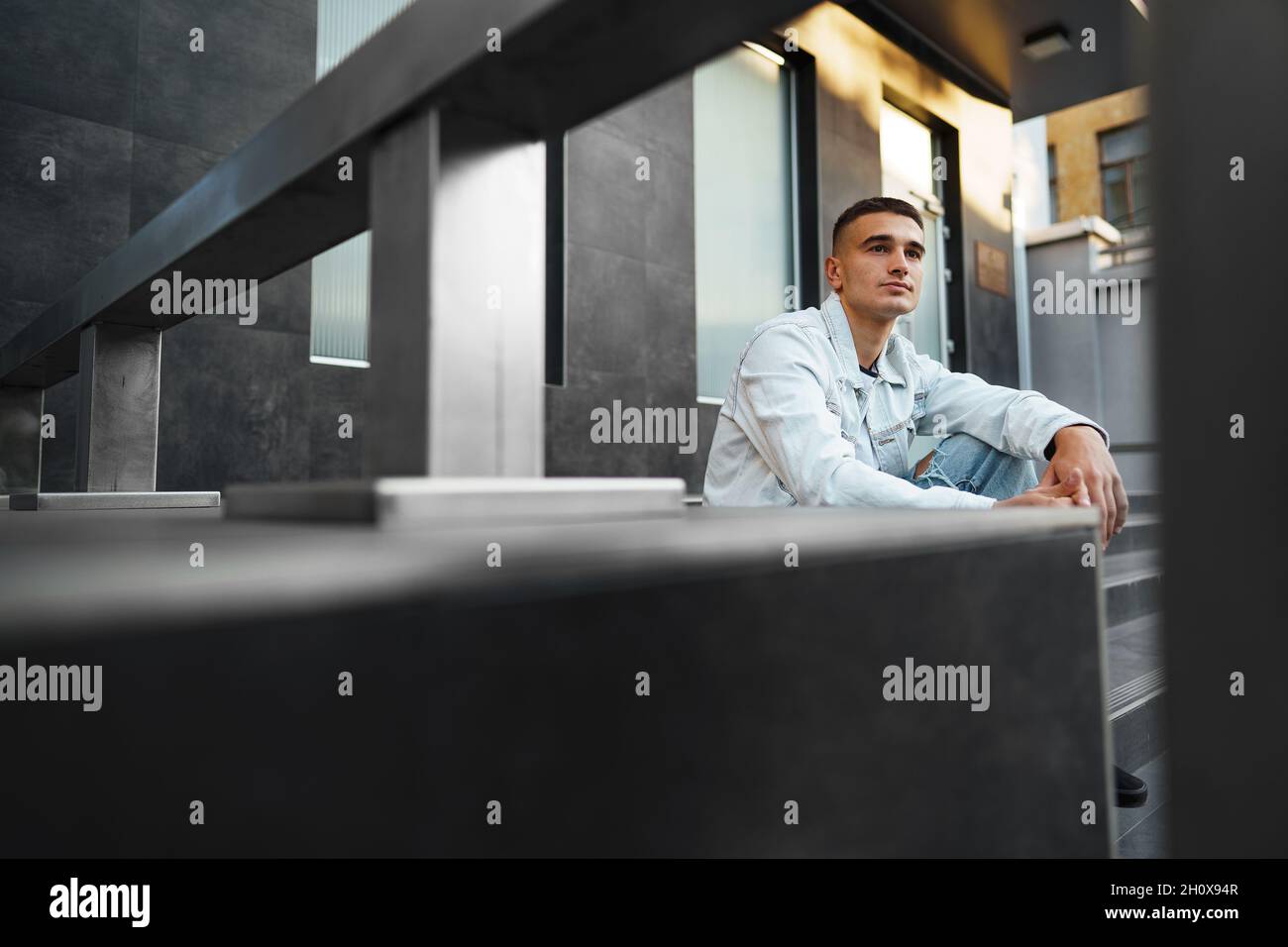 Young casual man sitting on stairs alone on street Stock Photo - Alamy