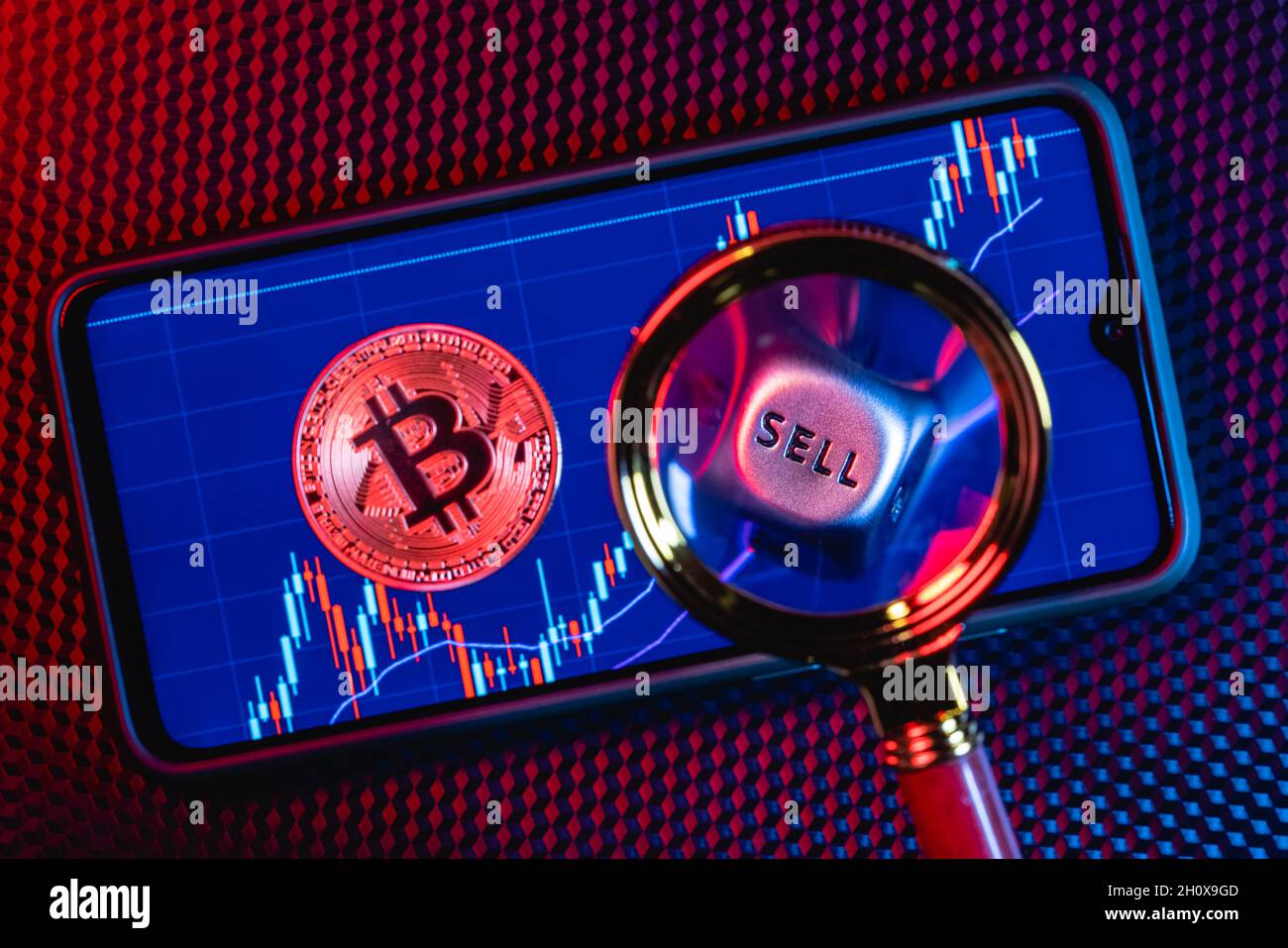 Bitcoin on the background of a smartphone screen with the image of stock candlesticks. Stock Photo