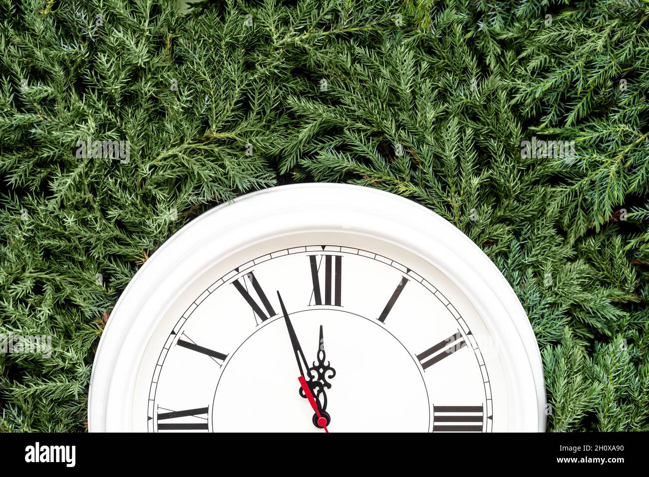 Half part of white clock on fir tree branches as background Stock Photo ...