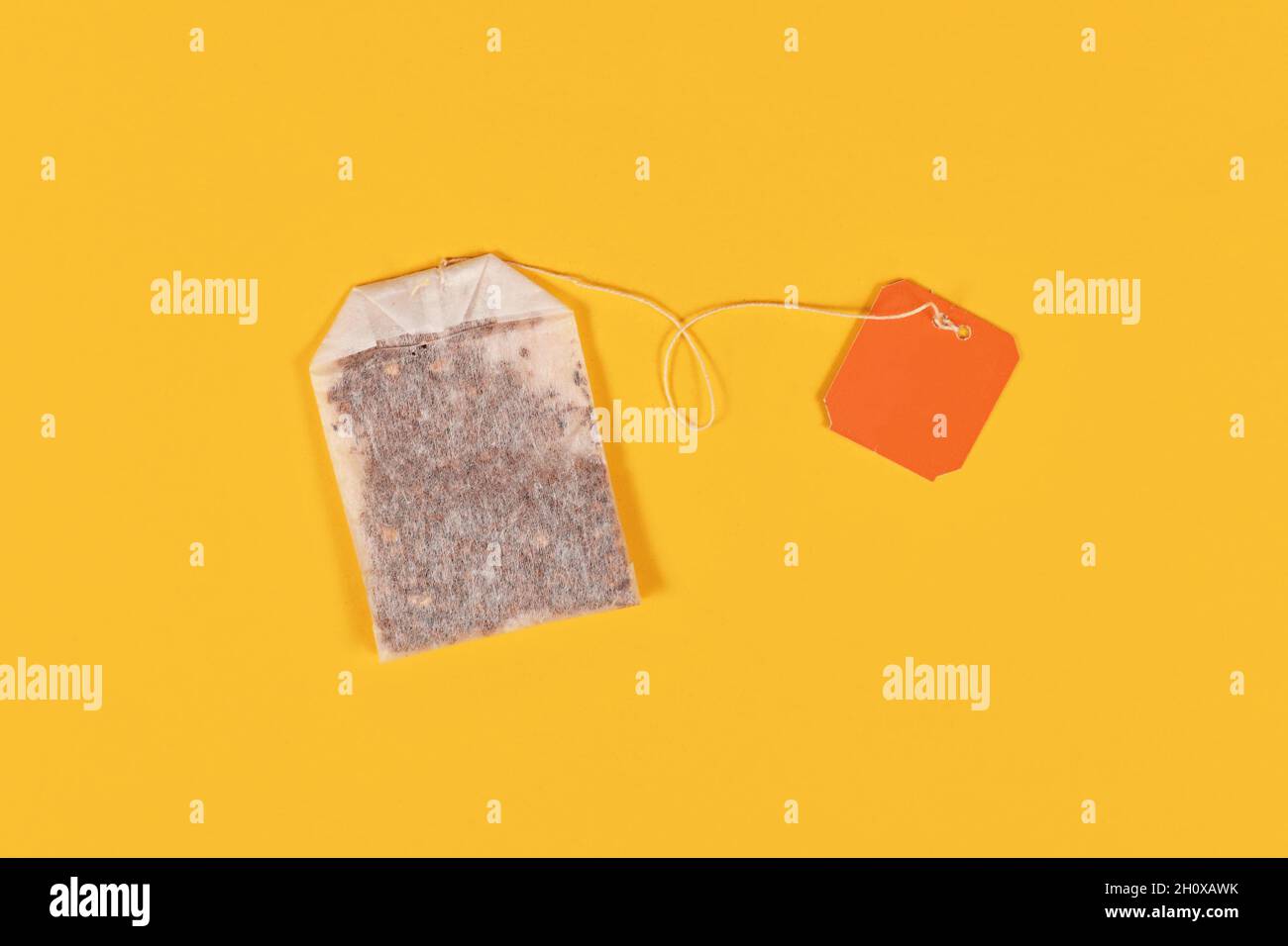 Tea bag with blank orange label on yellow background Stock Photo