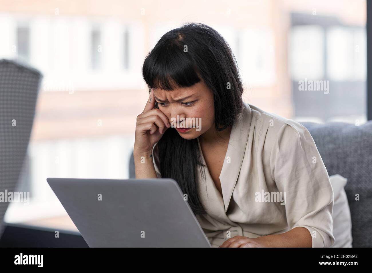 Woman frowning while using laptop Stock Photo