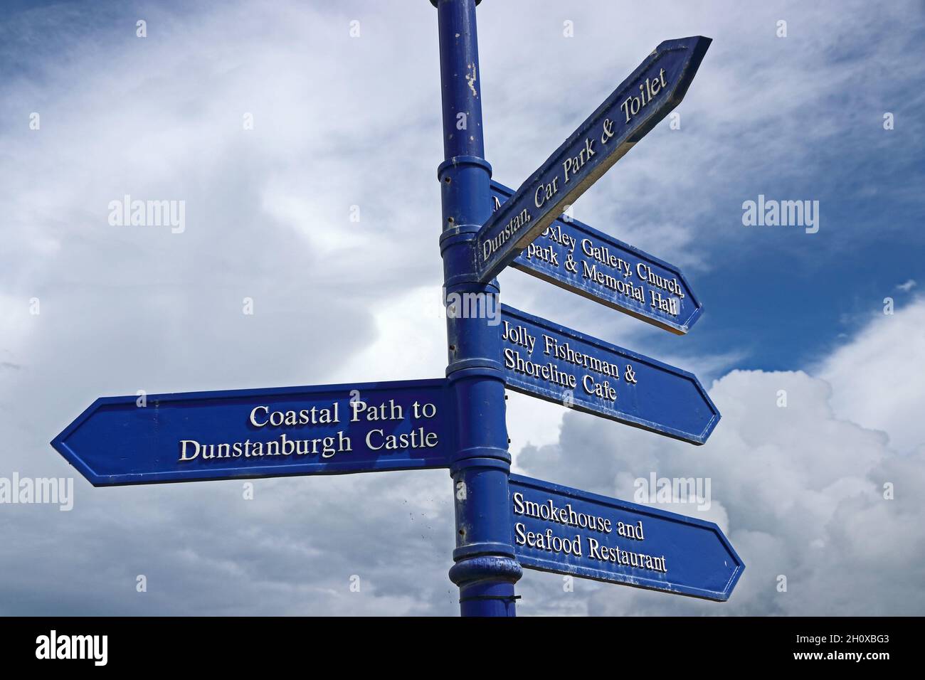 Blue visitors signpost showing directions of local points of interest, Craster Stock Photo