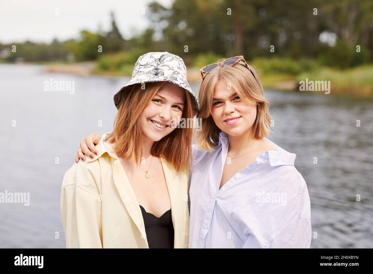 Two friends embracing at lakeside Stock Photo