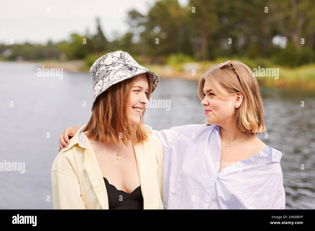 Two friends embracing at lakeside Stock Photo