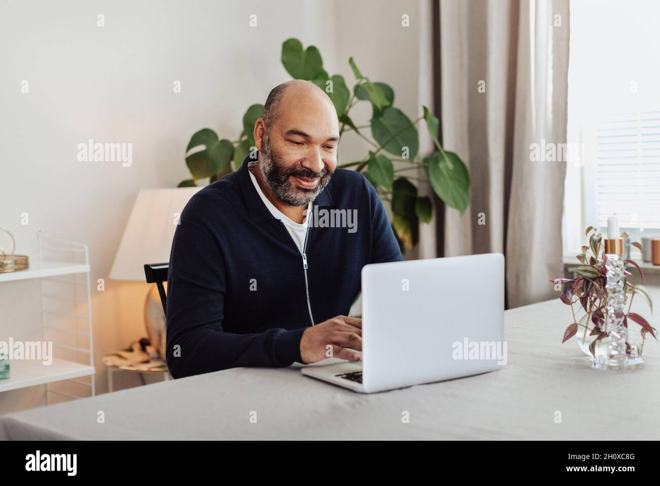Smiling man using laptop at home Stock Photo