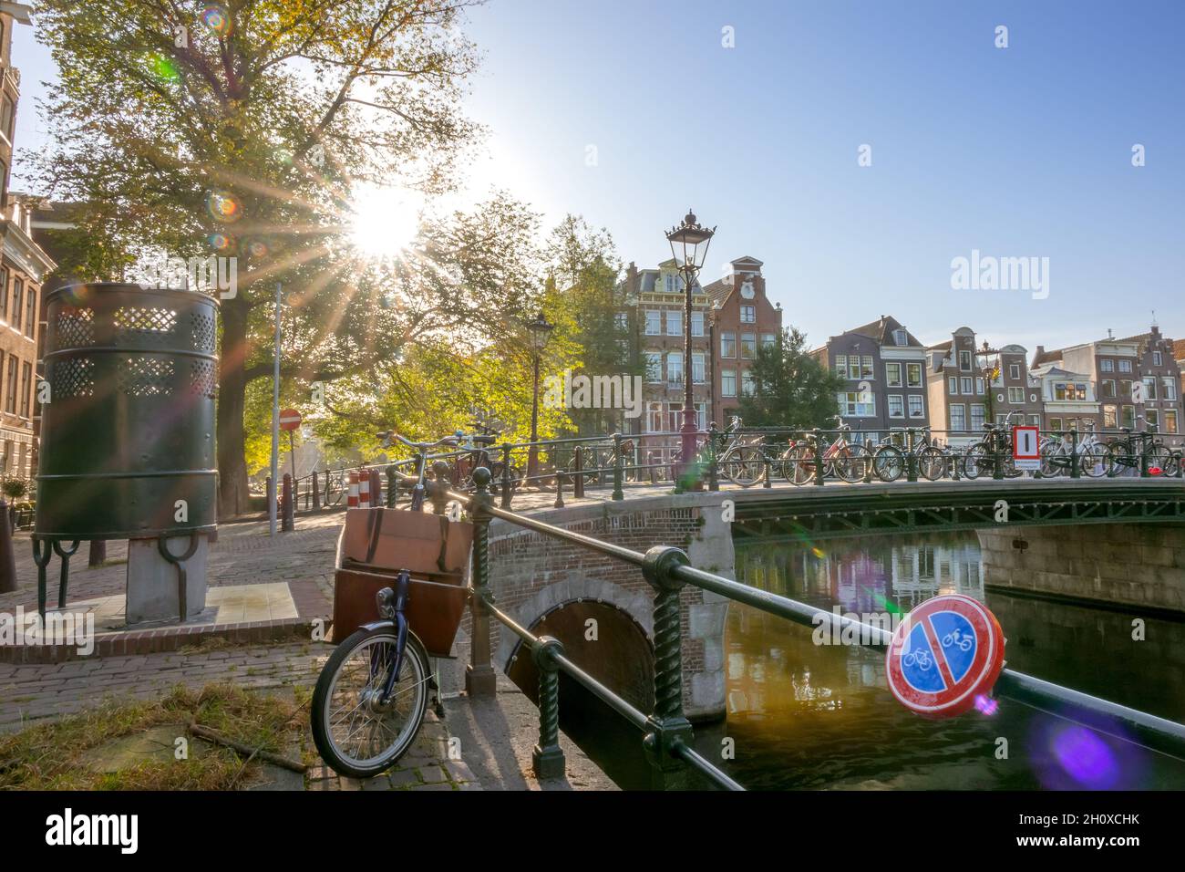 Netherlands. Sunny morning in Amsterdam. Traditional houses on the canal. Many bicycles near the fence of the bridge. Street male toilet Stock Photo
