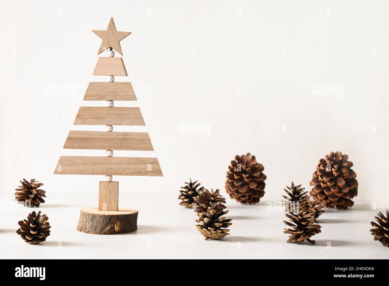Creative wooden alternative Christmas tree and pine cones on white background. DIY. Concept eco Xmas holiday. Zero waste. Stock Photo