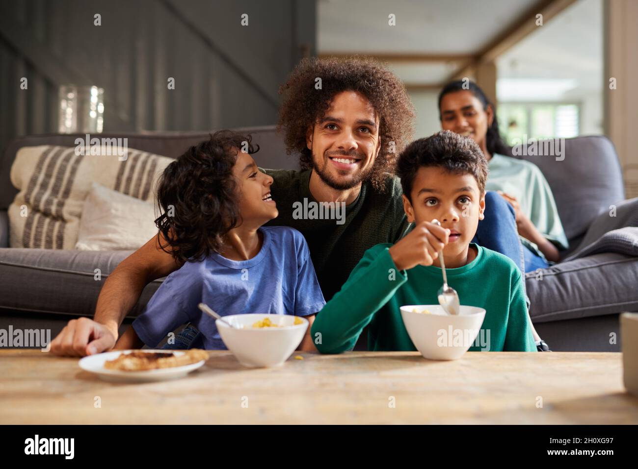 Father and sons watching TV in living room Stock Photo