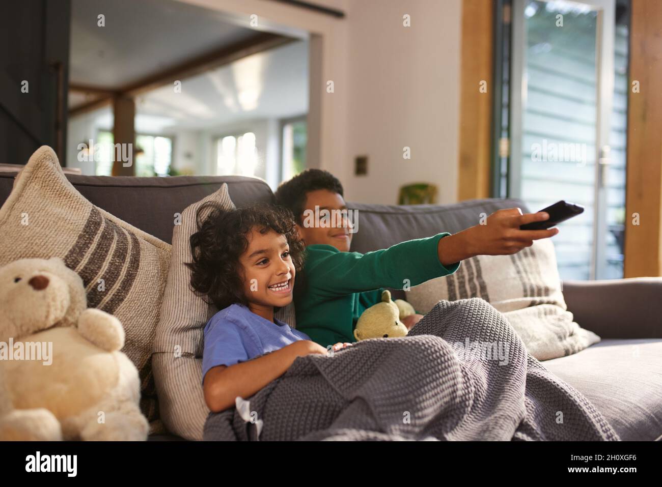 Two cheerful boys watching TV using remote control Stock Photo - Alamy