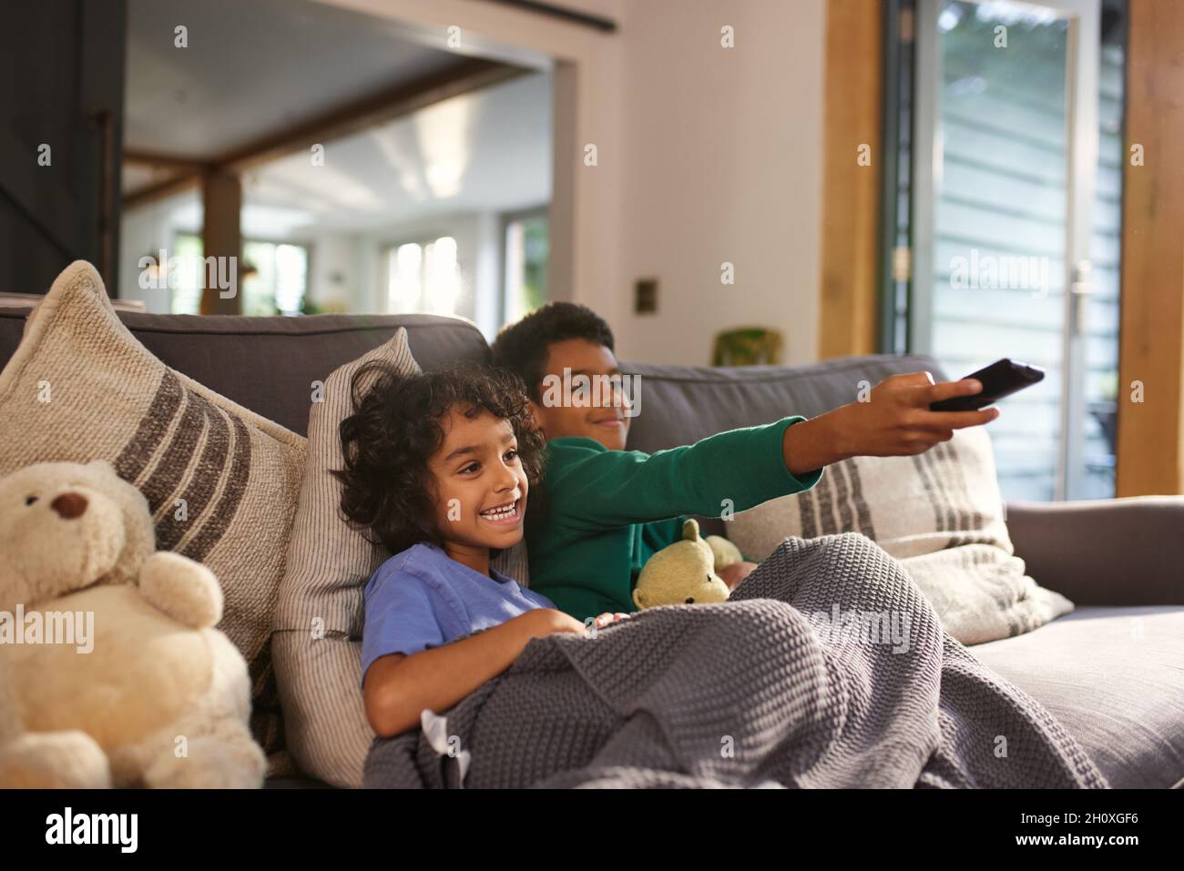 Two cheerful boys watching TV using remote control Stock Photo