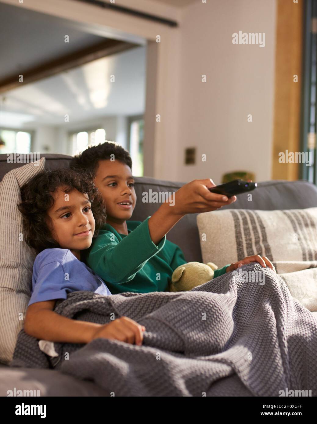 Two cheerful boys watching TV using remote control Stock Photo