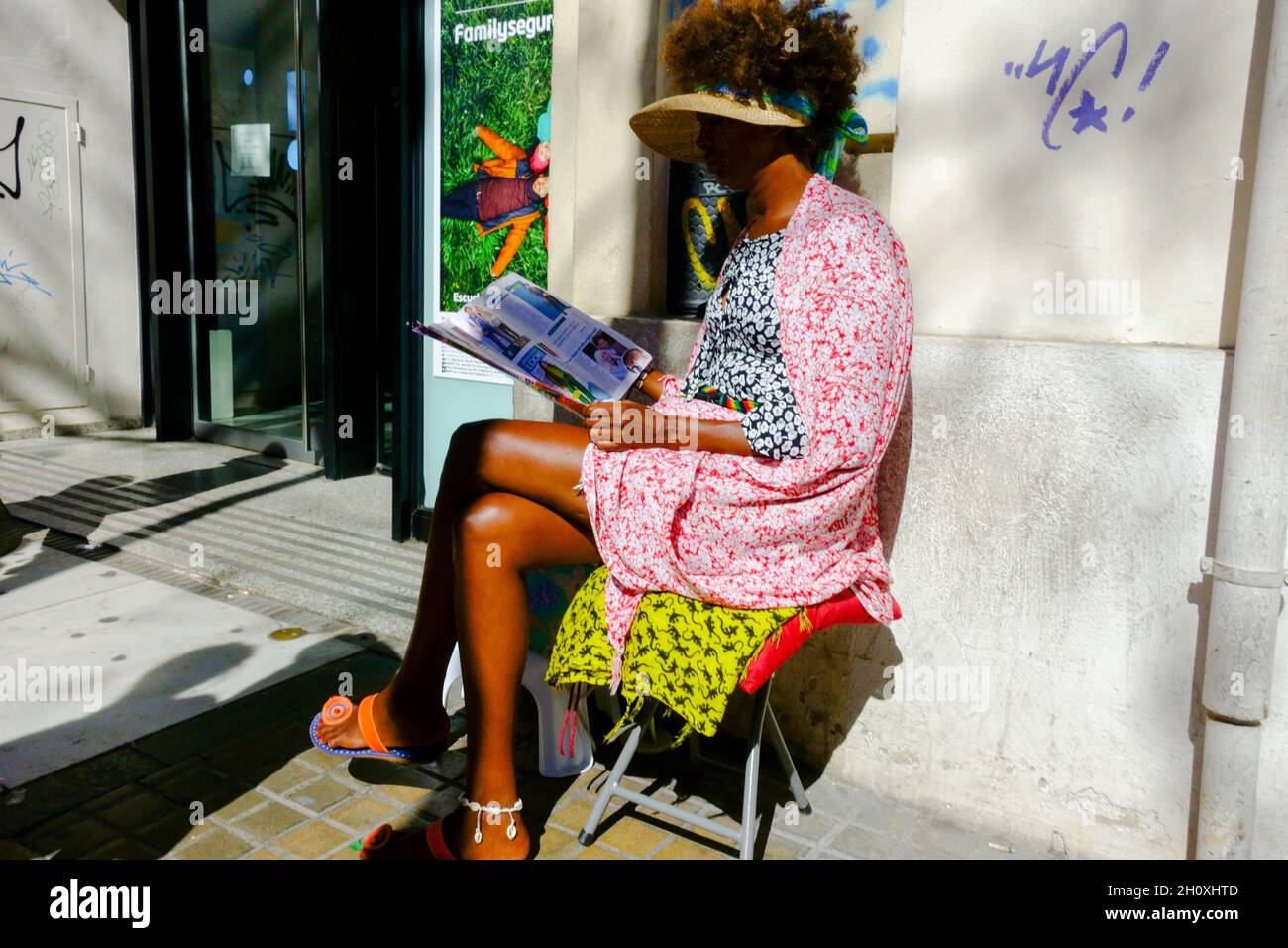 Afro-American woman reading magazine, Valencia street scene Spain Stock Photo