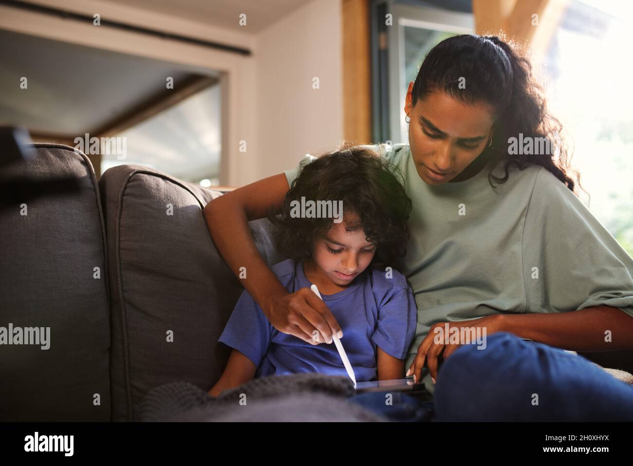Mother and son using tablet on sofa Stock Photo