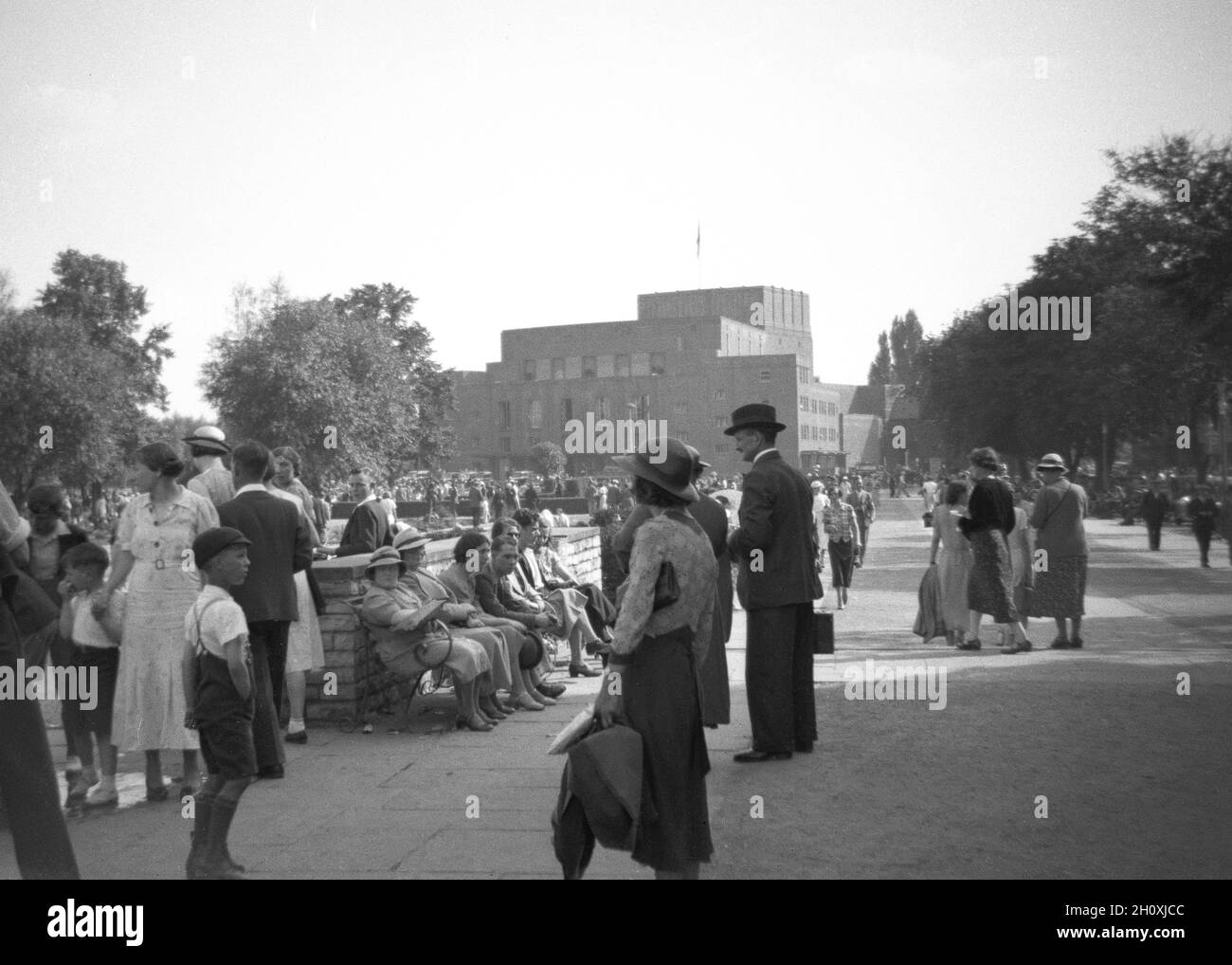 1930s, historical, a gathering of people in Bancroft Gardens beside the new Shakespeare Memorial Theare in Stratford-Upon-Avon, England, UK. The original Memorial Theatre had opened on the banks of the river Avon in 1879 and the one seen in the distance here, designed by a female architect, Elisabeth Scott and on a site next to the original one, opened in 1932 . In 1961, It was renamed the Royal Shakespeare Theatre, following the creation of the Royal Shakespeare Company (RSC) the previous year. Stock Photo