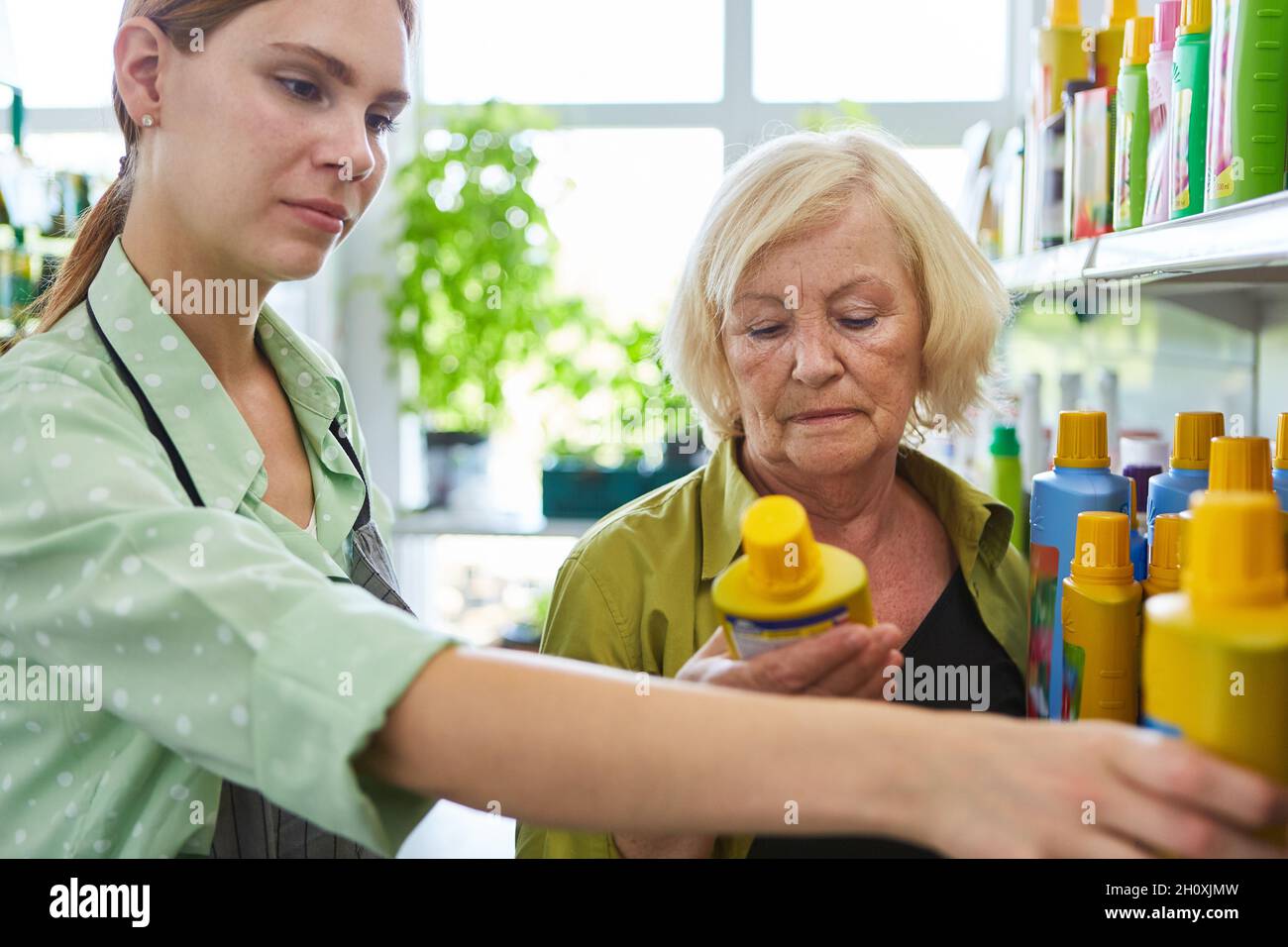Young woman as a saleswoman helps critical customer with shopping in the garden center Stock Photo