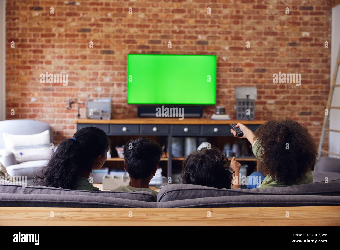 Family watching TV at home on sofa. Stock Photo