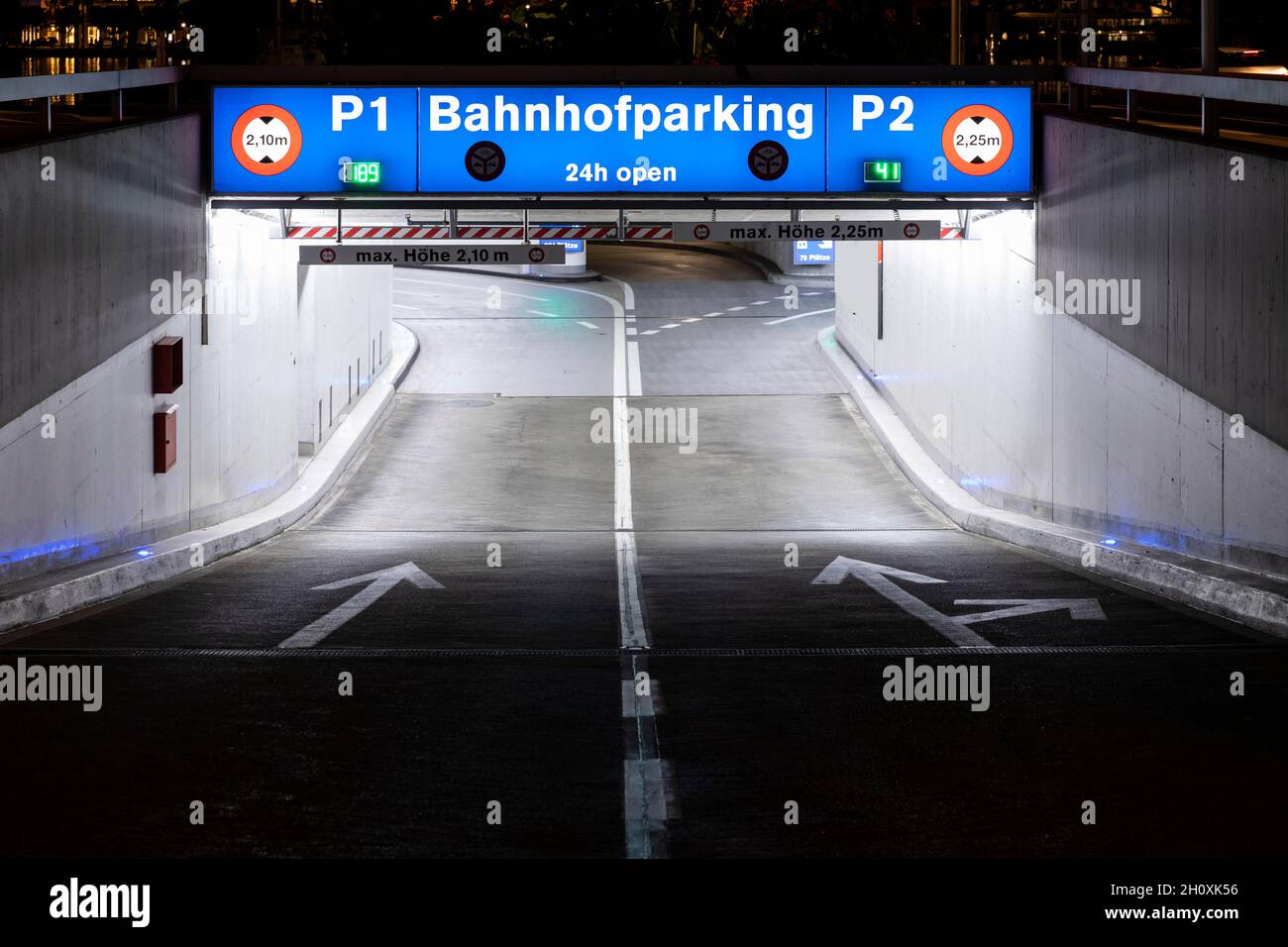 Underground car park entrance with german inscriptions in Luzern. Night view, illuminated by lights. Street signs on the ground. Stock Photo