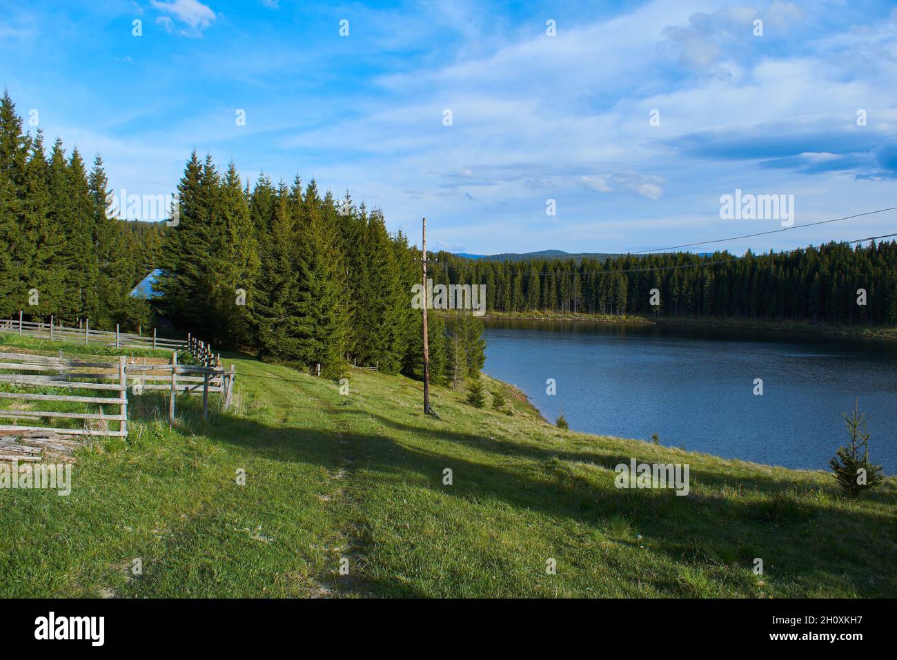 A view over the Lake Oasa in Mountains Sureanu with sky with clouds and forest Stock Photo